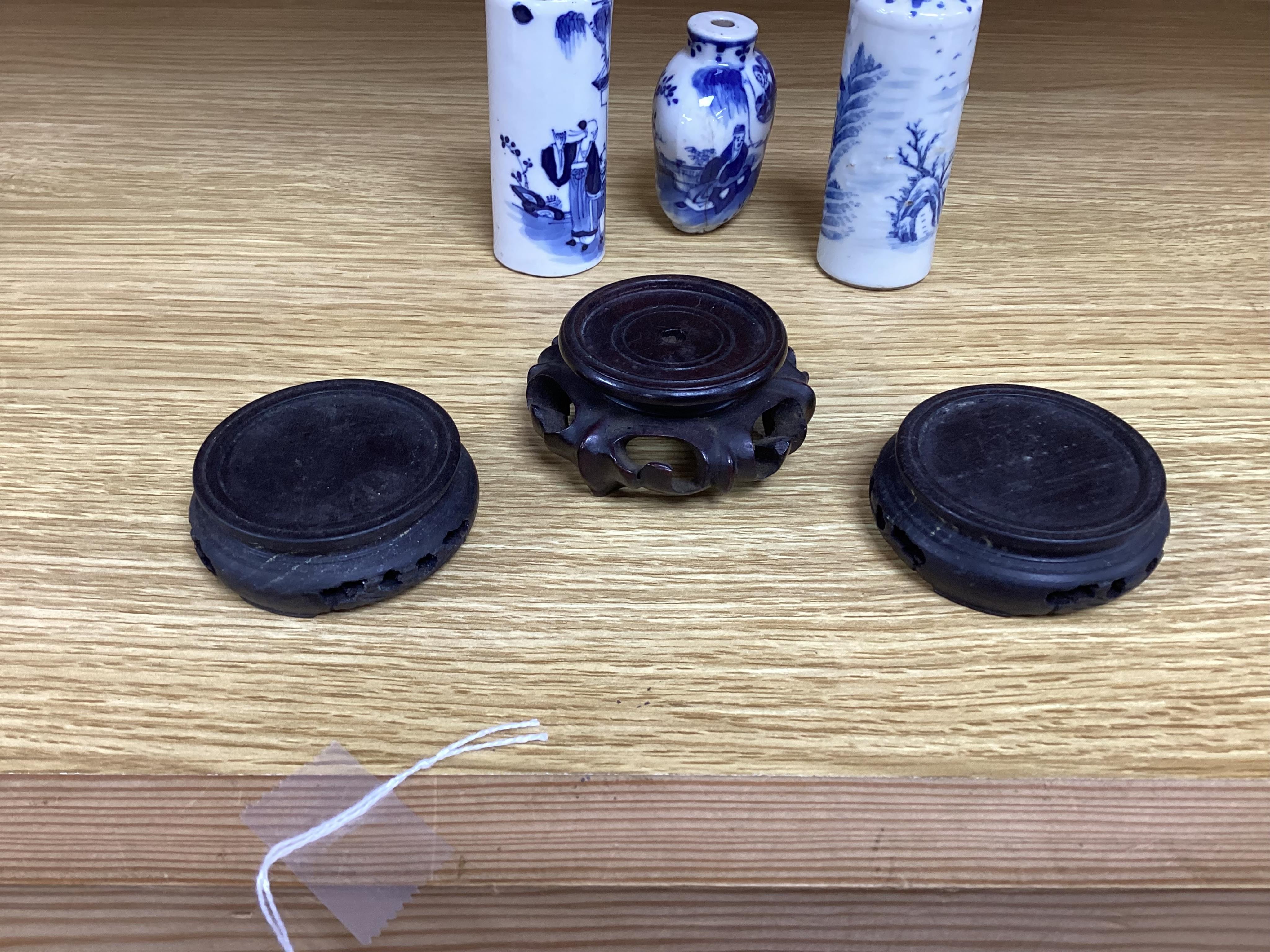 Three Chinese blue and white snuff bottles and three hardwood stands, largest 8cm high. Condition - poor to fair